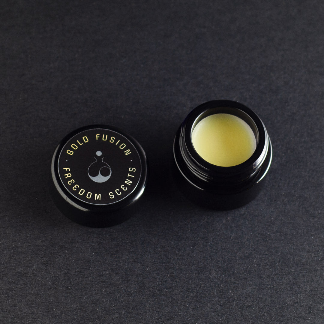 solid perfume balm made in the uk with natural ingredients on a dark grey background in a black glass jar with lid open showing solid perfume in the jar