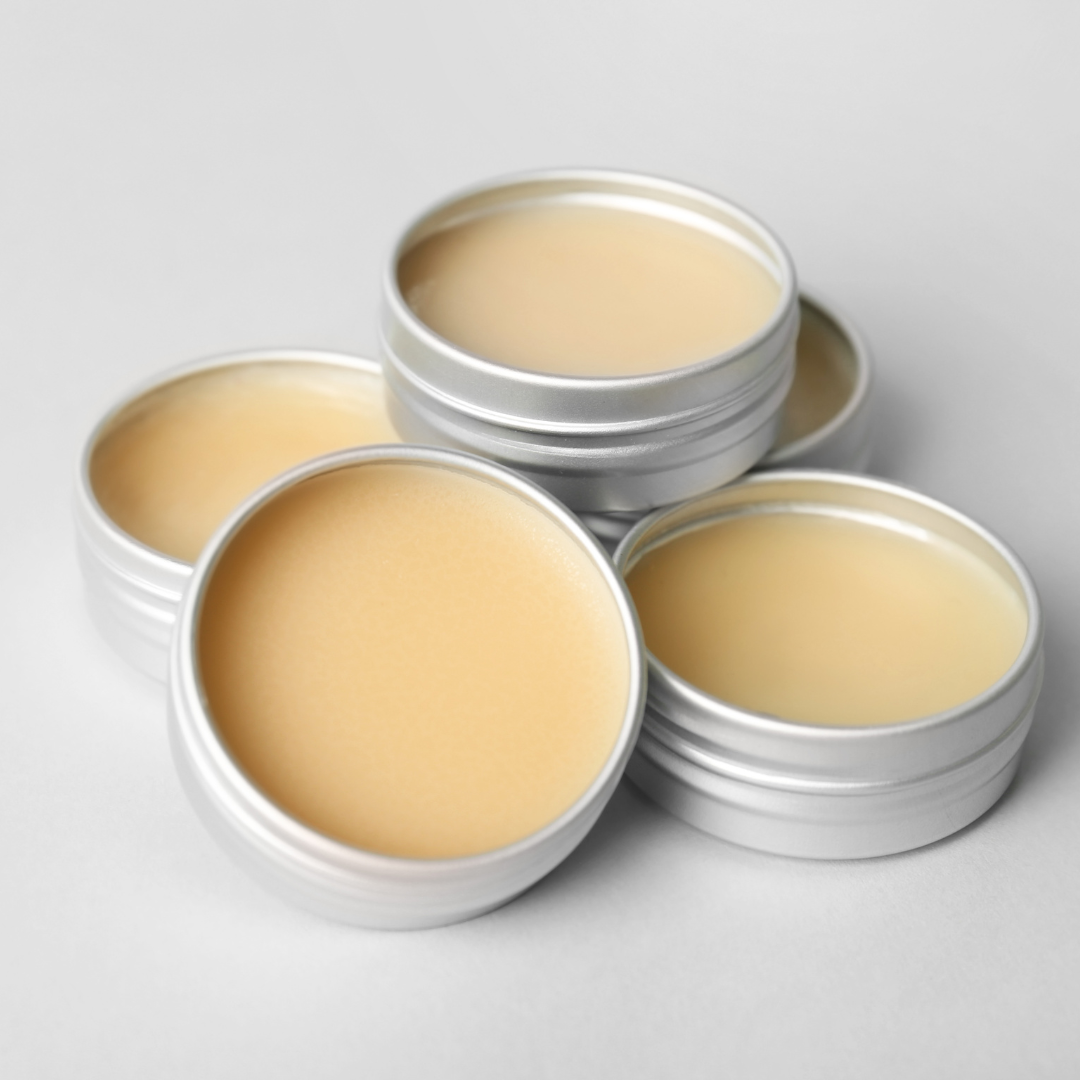 five metal tins which are open and displaying a yellow creamy lip balm inside