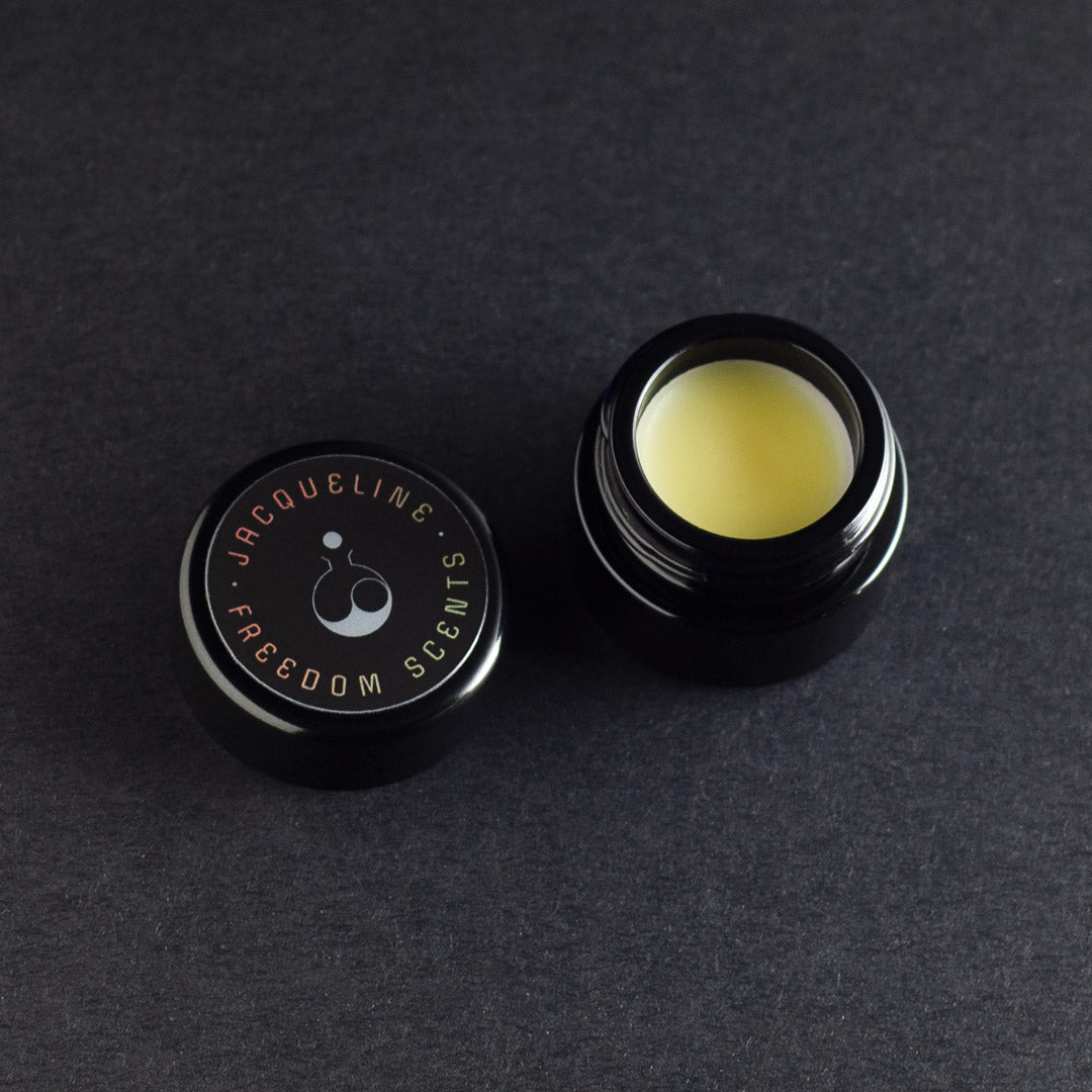 solid perfume jar with open lid and black glass jar and fragrance balm inside