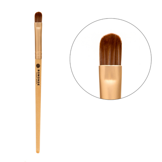 photo of bomonde's make up brushes. the brushes have a wooden bamboo handle, gold matte metal accent and the bristles are a chestnut coloured synthetic bristle that is certified cruelty free. the image shows the full length of the cruelty free make up brush on the left and in a circle to the right a close up of the bristles. this make up brush is a large flat eyeshadow brush which is used to apply eyeshadows, eye liners etc