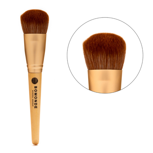 photo of bomonde's make up brushes. the brushes have a wooden bamboo handle, gold matte metal accent and the bristles are a chestnut coloured synthetic bristle that is certified cruelty free. the image shows the full length of the cruelty free make up brush on the left and in a circle to the right a close up of the bristles. this make up brush is a large fluffy brush that's used to apply finishing powder, primer or foundation powder