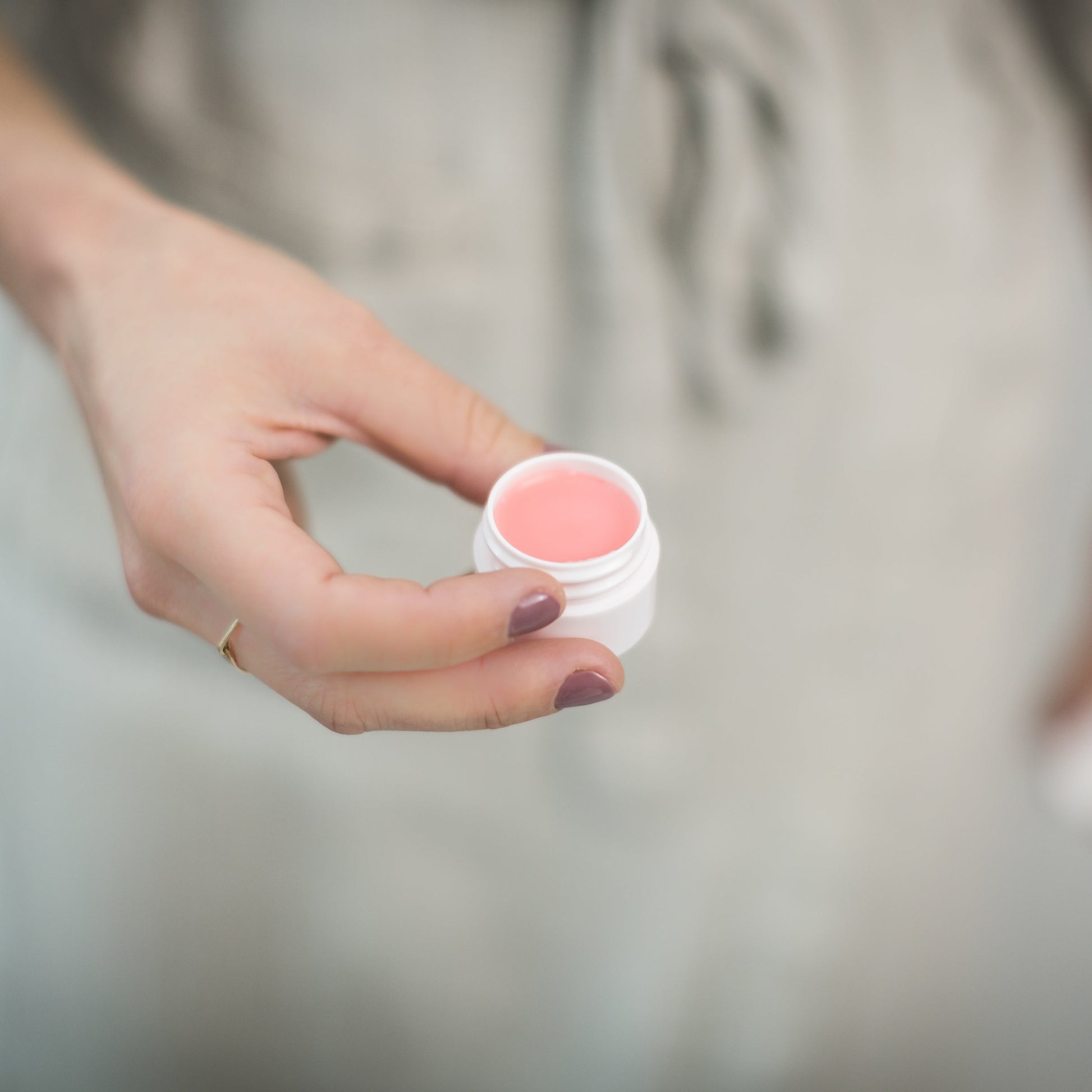 Woman holding a beauty product from vegan beauty brands.
