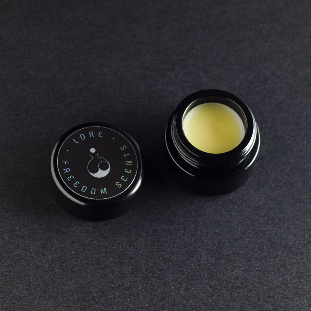 open jar of solid perfume on a grey background