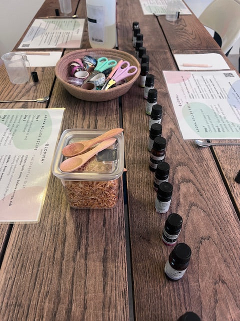 wooden table laid out with aromatherapy workshop worksheets, essential oils and craft supplies