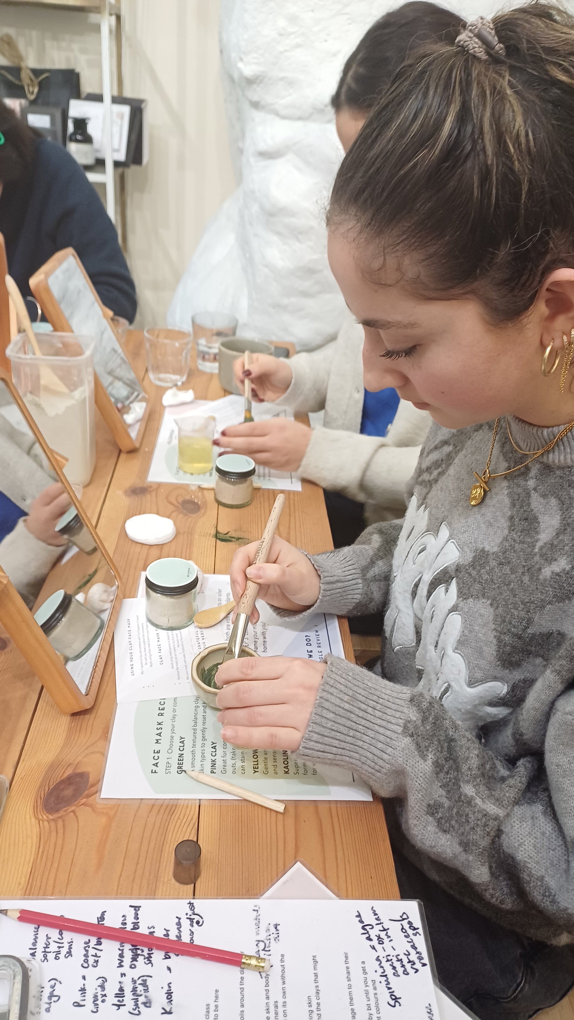 Two people working on a craft project at a table with various materials.