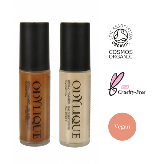 odylique foundations on a white background. Showing two of the 12 shades of natural mineral foundation, a dark tan and a creamy white one. the foundations are in tall glass bottles with a black lid. to the right is the soil association cosmos organic logo, the peta cruelty free logo and a vegan friendly stamp