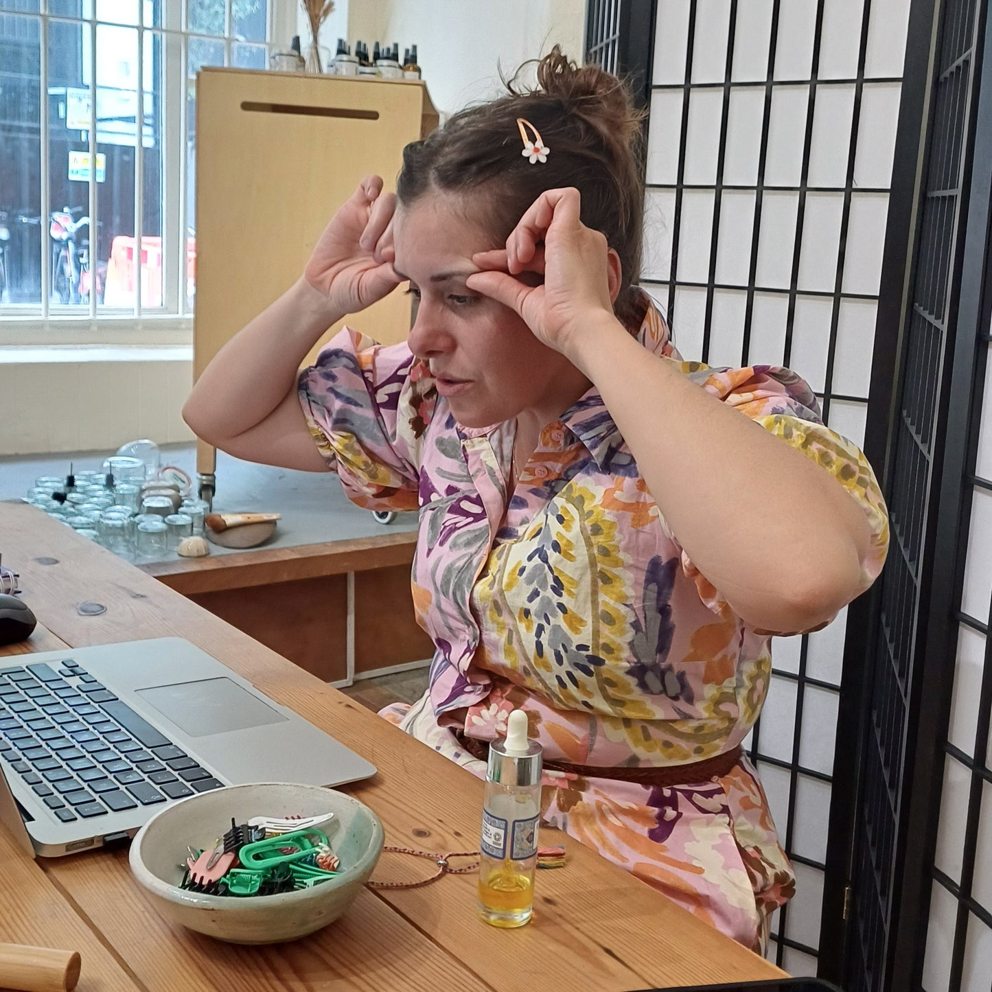 woman at a laptop demonstrating face massage techniques at an online class