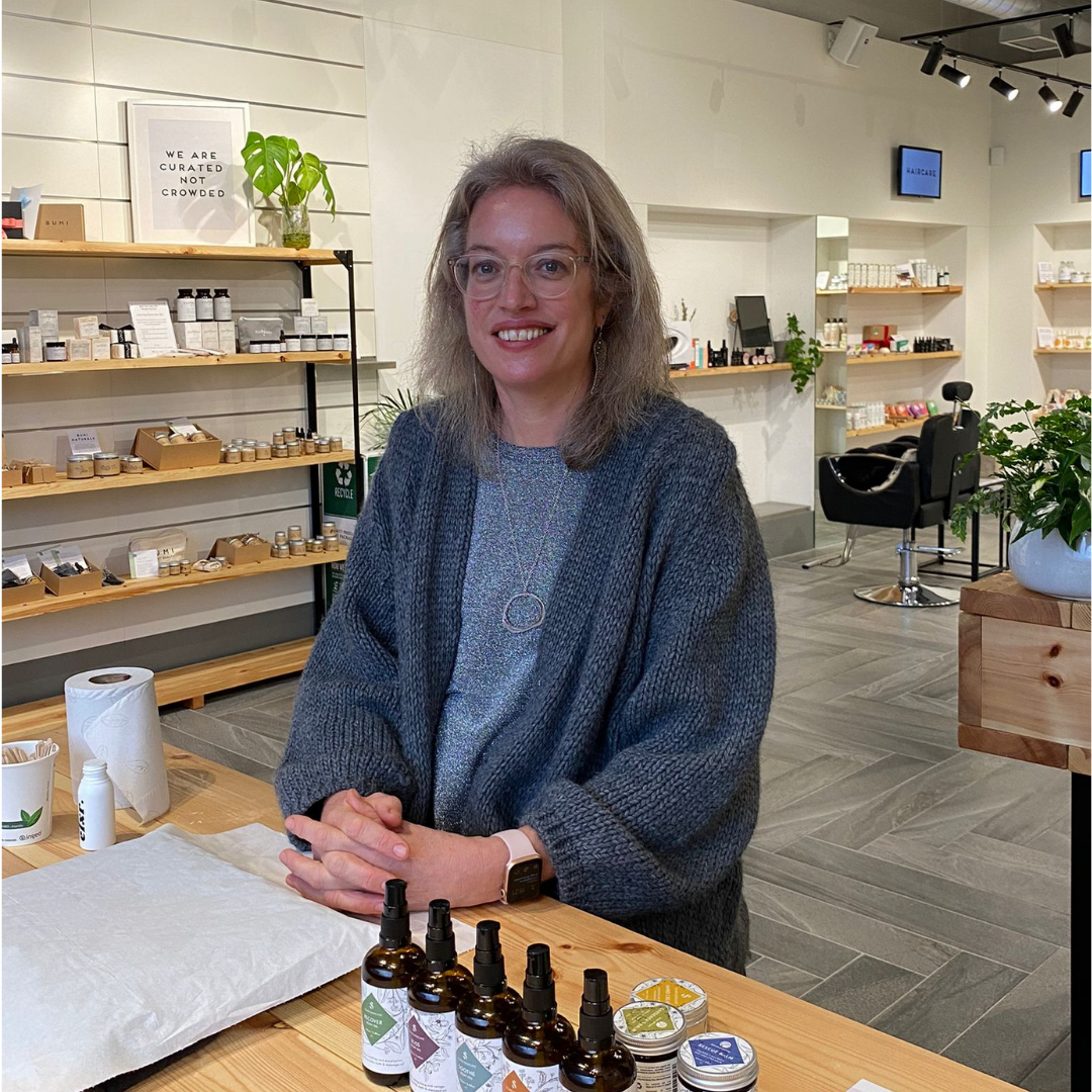 silvan skincare founder marian in the blomma beauty store in coal drop yards kings cross london. at the table where she is sitting are the various products used to give customers an indulgent hand treat including massage oils, balms and hand creams