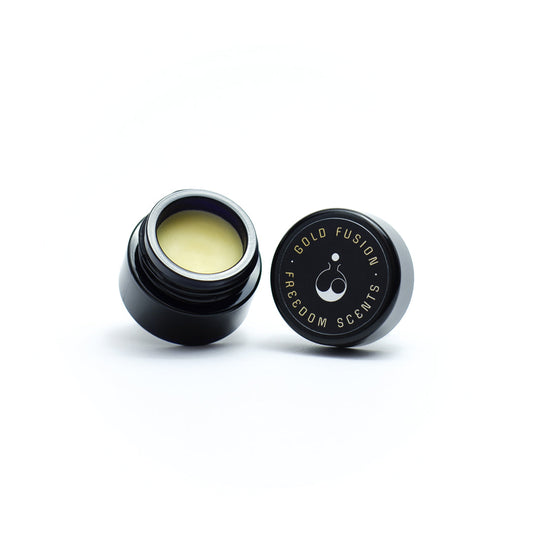 solid perfume balm made in uk in a glass jar with lid and perfume balm visible on white background
