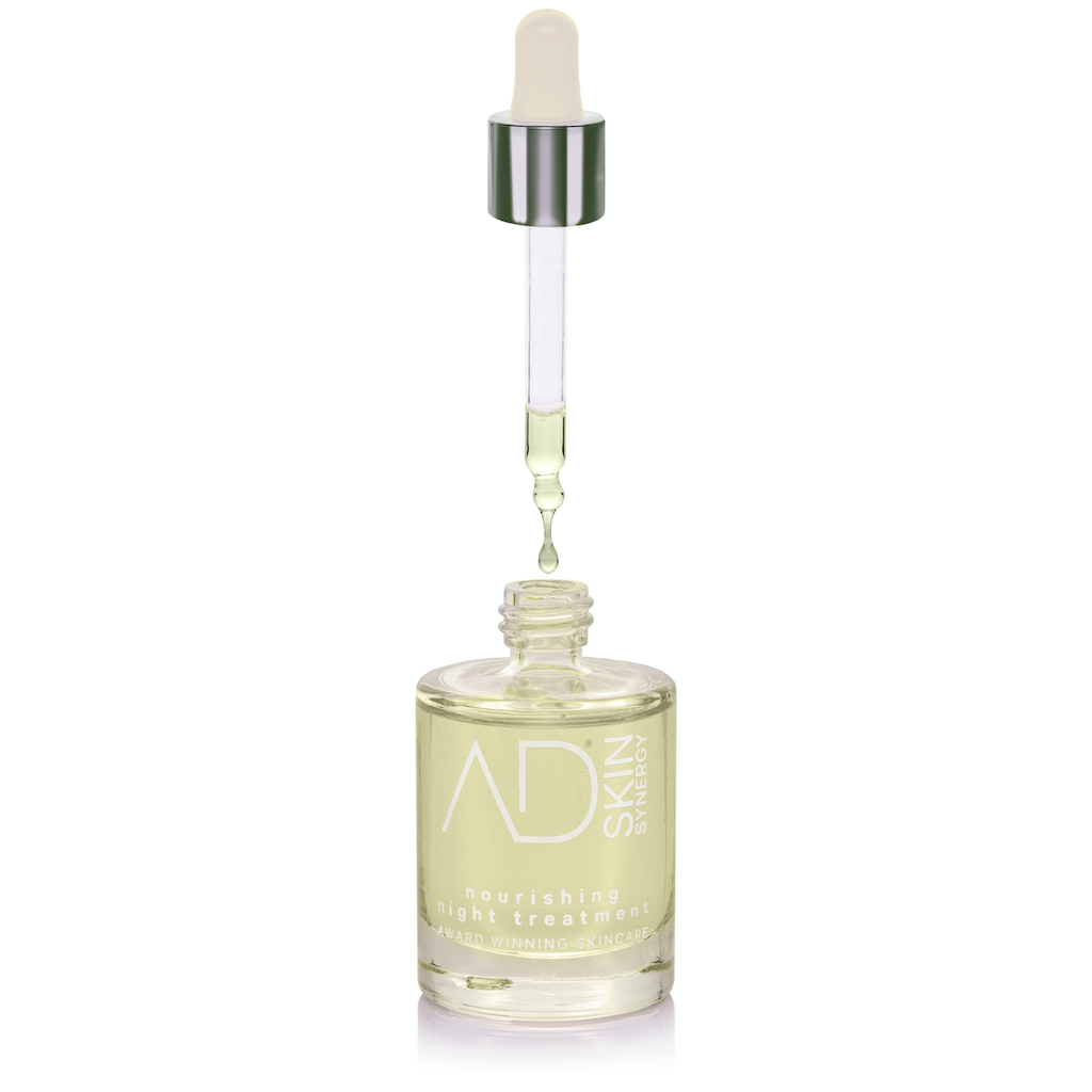 AD Skin Synergy Nourishing Night Treatment. Natural skincare. Dry skin treatment. Pictured in a glass bottle with pipette floating above and a drop of oil falling into the bottle.