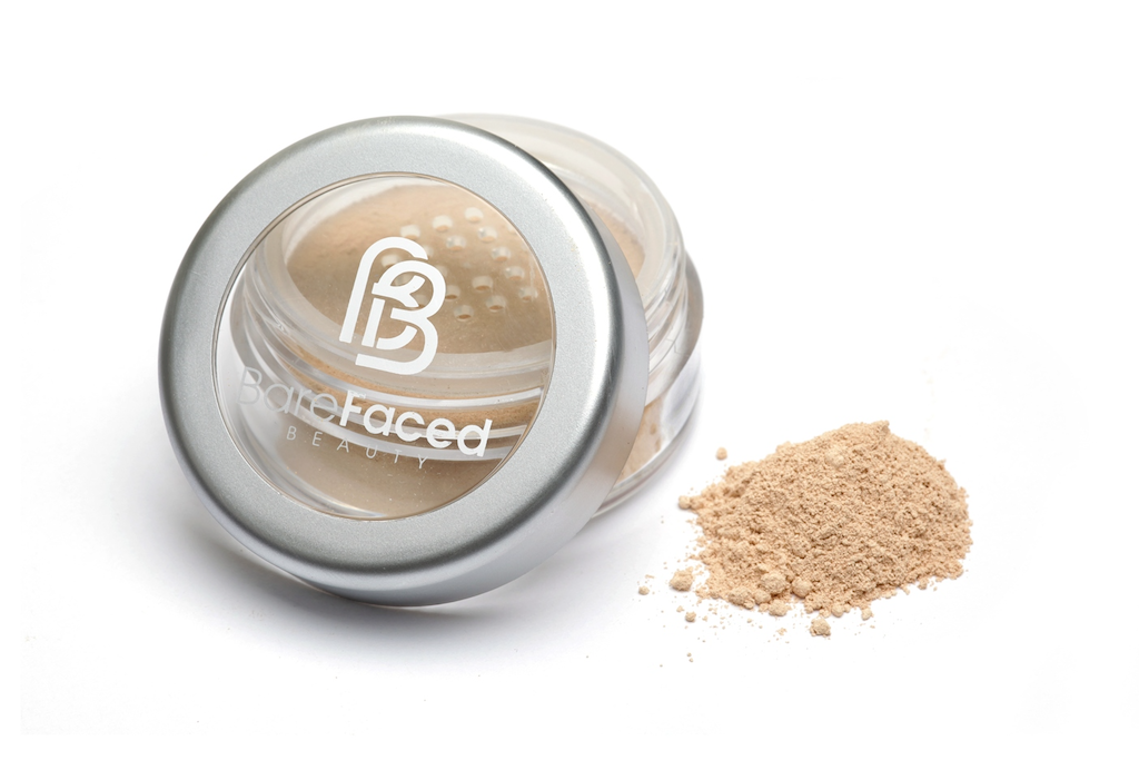BareFaced Beauty Natural Mineral Foundation in Innocent. Ethical mineral foundation. The powder mineral foundation is pictured in a clear plastic jar with a small pile of the powder sitting next to it.