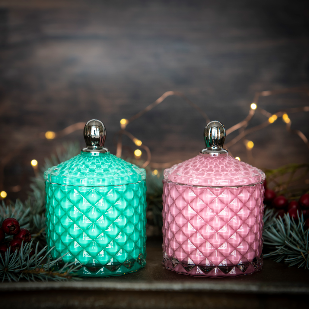 2 candles, pink and green side by side in christmassy background