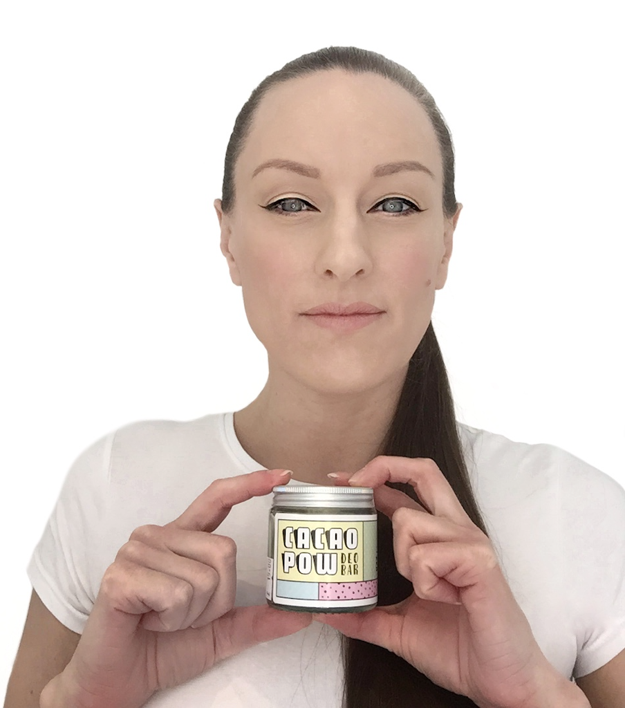 Cacao Pow Natural Deodorant Founder Tonya. Tonya is pictured holding a jar of her deodorant in a white t-shirt with black winged eyeliner.