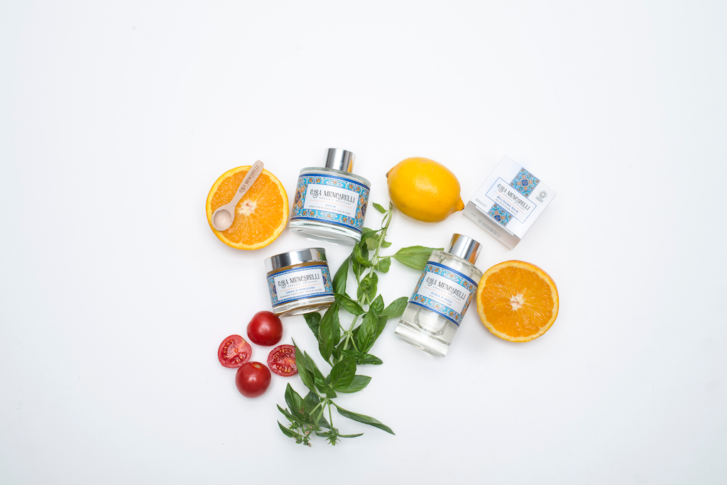 Casa Mencarelli Crema Di Pomodoro Nourishing Tomato Night Cream & Cleanser. Essential oil free moisturiser. The cream is pictured with Casa Mencarelli's mask and toner, alongside a sliced orange, whole lemon, basil and tomatoes.