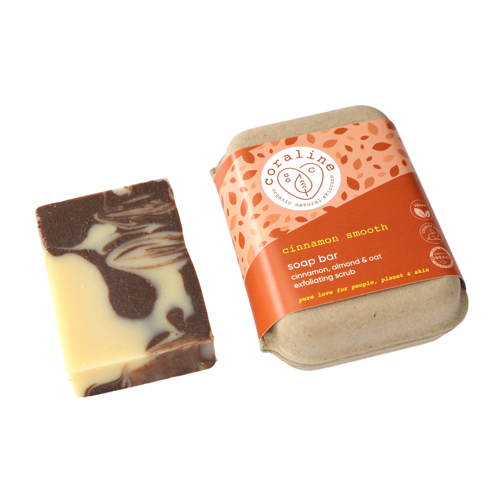 handmade organic soap with a yellowy creamy colour and brown cinnamon coloured swirls in it. Next to a brown kraft soap box and orange and yellow sleeve on white background