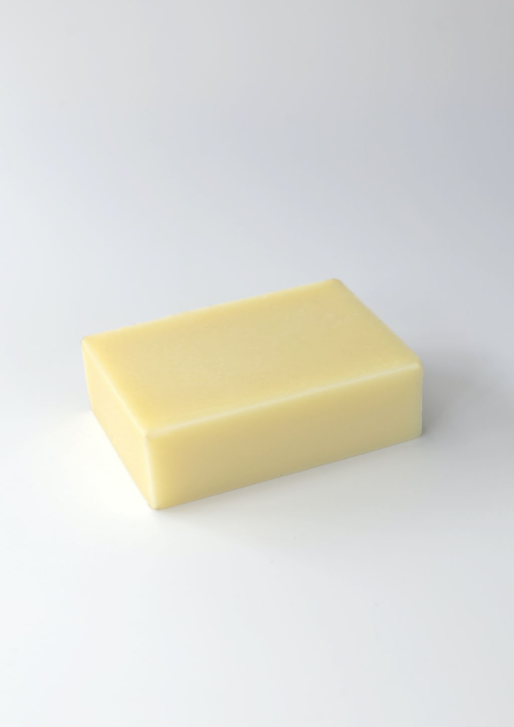 A single bar of pale yellow soap centered on a clean, white background.