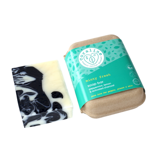 A bar of the minty fresh soap - a white soap bar with dark blue marbling placed next to its eco-friendly packaging. The packaging is brown recycled carton with a green label that reads "minty fresh," with “peppermint, lemon & activated charcoal," 
