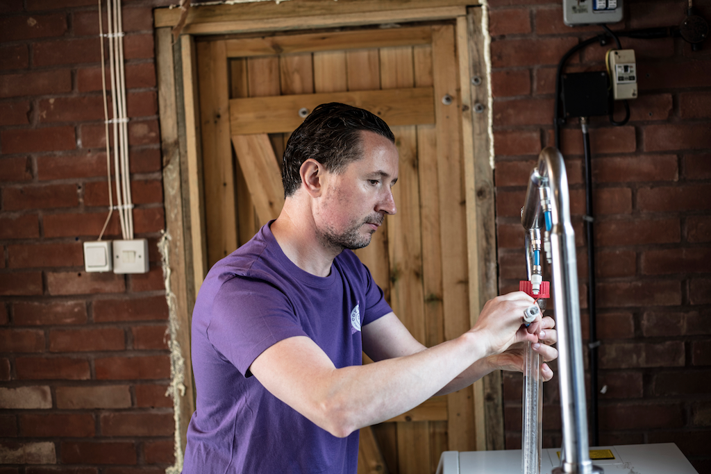 Coraline Skincare Founder Kevin, who is shown in a purple t-shirt making soap.