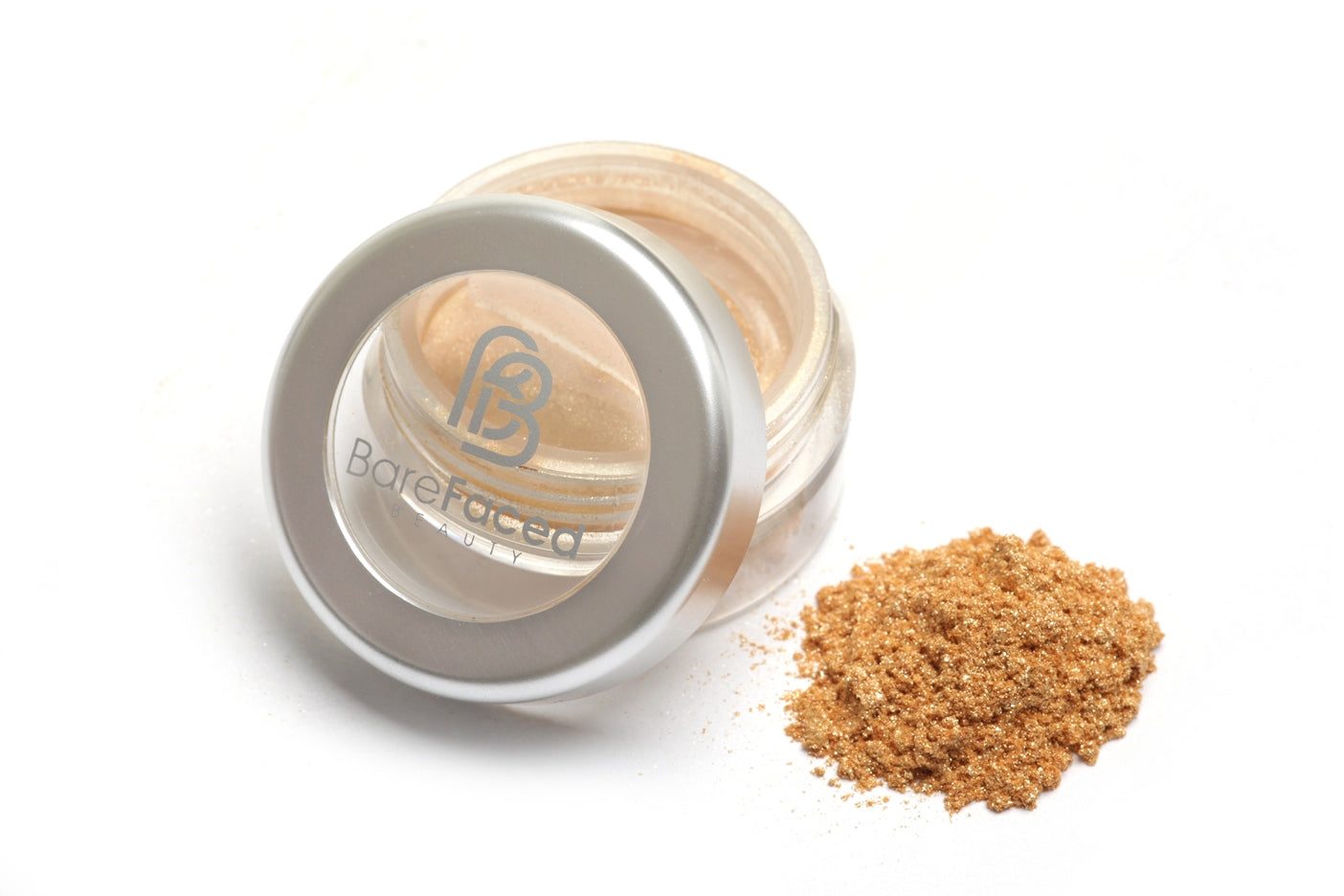 A small round pot of mineral eyeshadow, with a swatch of the powder next to it showing a light shimmery gold shade