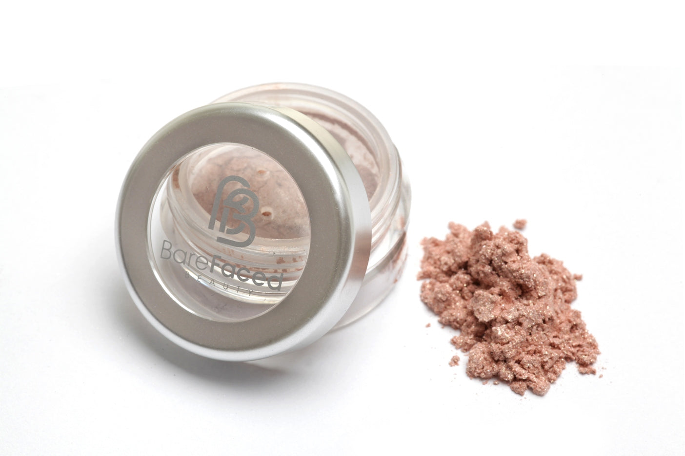 A small round pot of mineral eyeshadow, with a swatch of the powder next to it showing a shimmery apricot shade