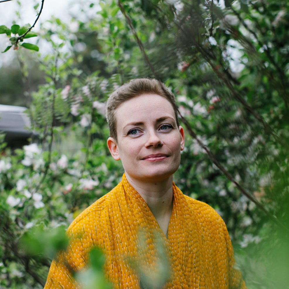 Forage Botanicals Founder Natasha. She is wearing a golden yellow robe and standing in the midst of a blooming floral tree.