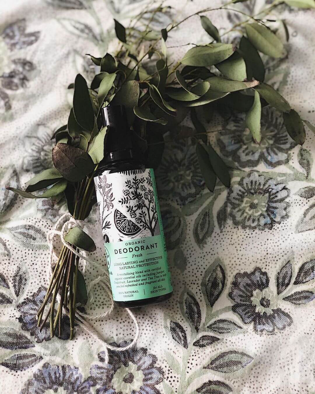 Haoma Organic Spray Deodorant. Certified organic deodorant without bicarbonate of soda. The Fresh deodorant is sitting on a black and white tablecloth with a bunch of dried eucalyptus behind it.