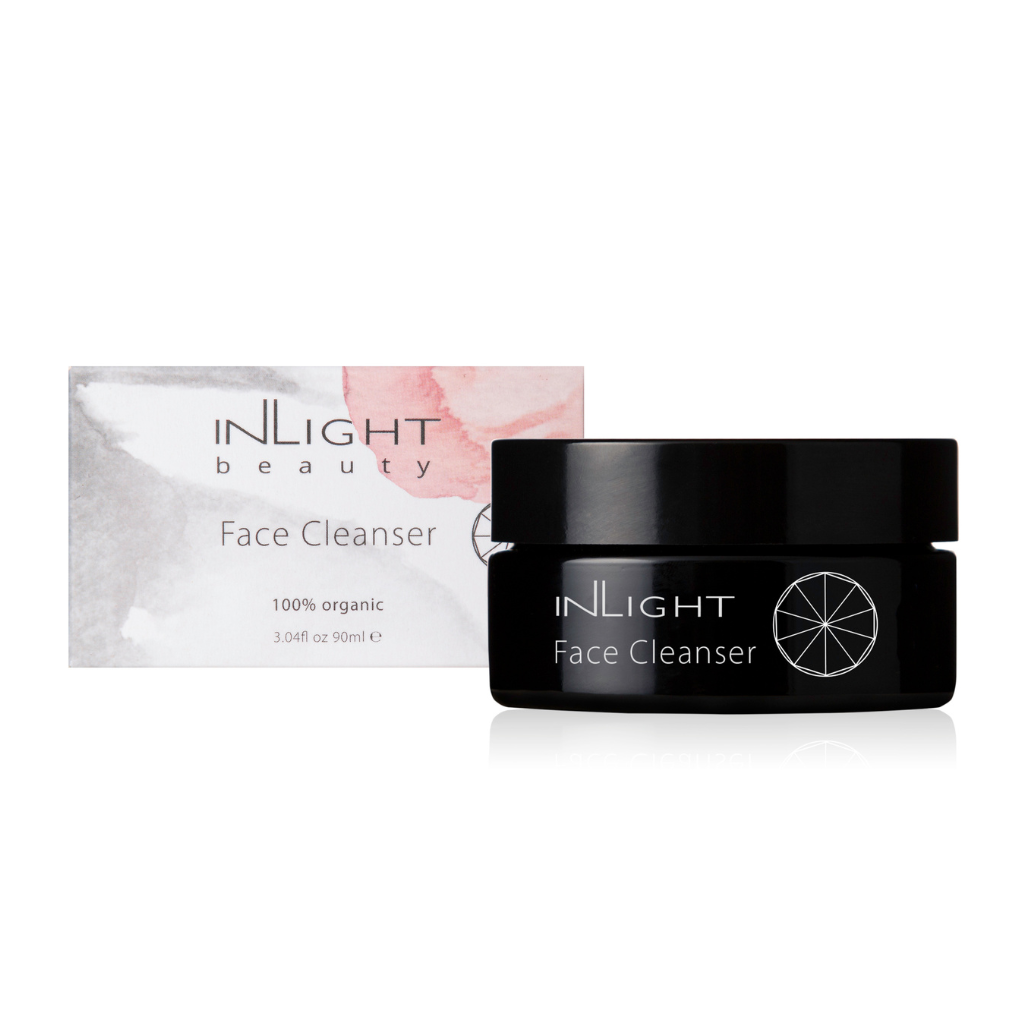 inlight beauty 100% organic face cleanser in a black glass jar with a black plastic lid. sitting next to the box which is white with grey and pink blush tones splashed across it on a white background. 