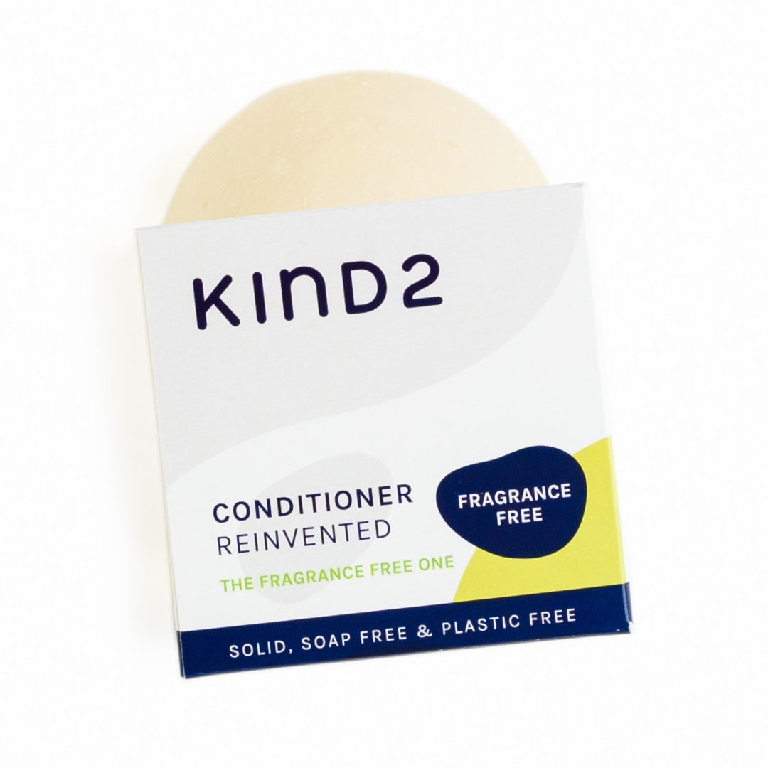 An image of the white/grey cardboard box of the fragrance free KIND2 conditioner bar with a partial view of the bar in it