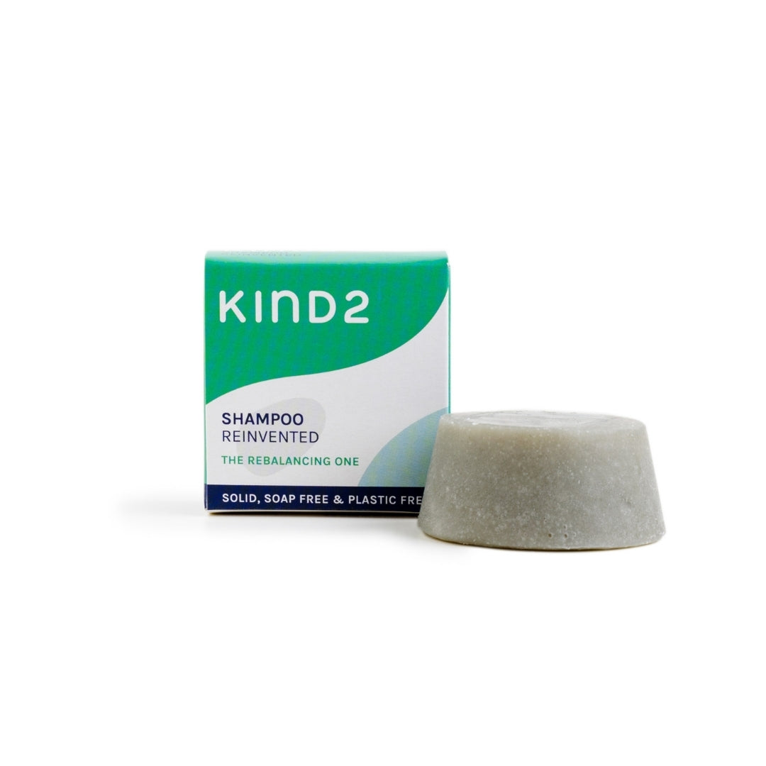 Small discovery size KIND2 shampoo bar. Placed next to the small, square green and white box it comes in.