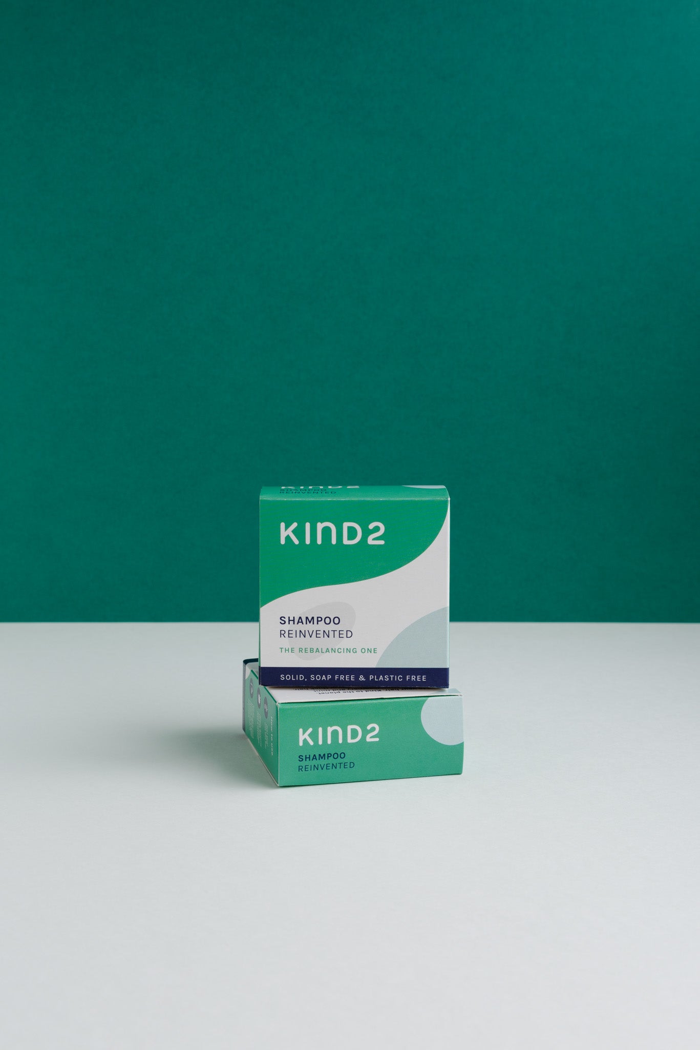 Sustainably packaged cardboard boxes of the KIND2 shampoo bars against a green and white background