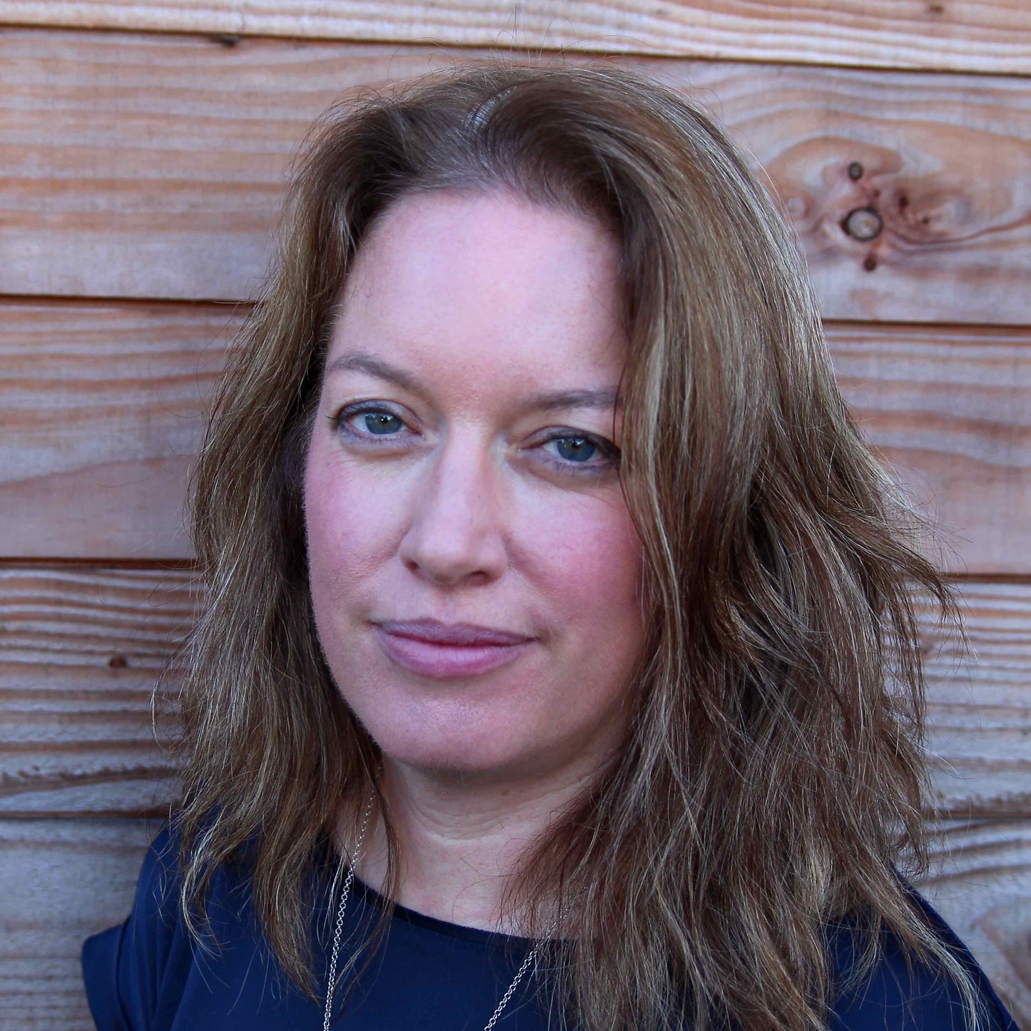 Silvan Skincare founder Marian in a blue shirt against a slat wood backdrop.