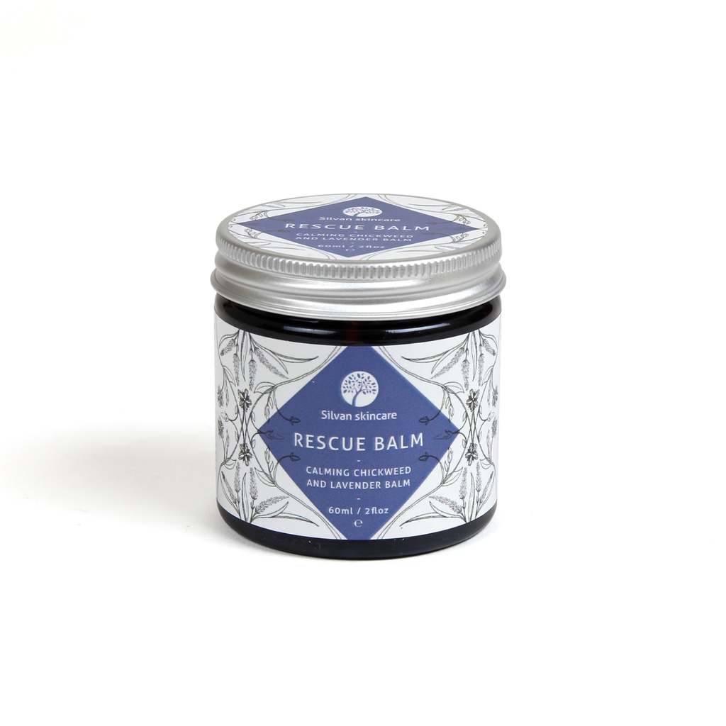 Silvan Skincare Rescue Balm. Natural skin remedies. The balm is pictured in an amber glass jar with an aluminium lid, labeled in white and blue with fine illustrations of flowers in black.