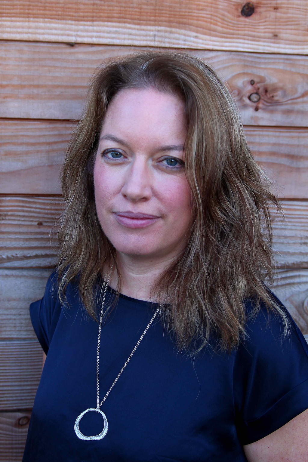 Silvan Skincare founder Marian in a blue shirt against a slat wood backdrop.