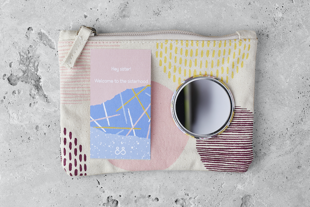 &Sisters My First Period Pack. Sustainable period products for teenagers. A small round mirror and a leaflet are sitting on top of an organic cotton zip-up pouch for holding feminine care products on the go.
