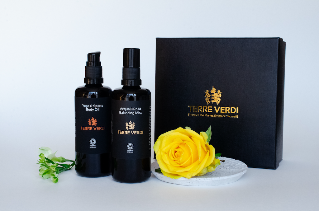 Terre Verdi Athletic Gift Set. Natural bodycare gift set. Both products are in black bottles and stand next to a luxury black box embossed in gold with the Terre Verdi logo. There is a large yellow rose sitting on a plate in front of the box.