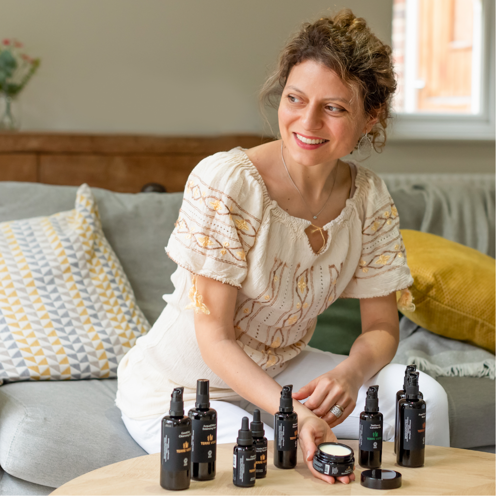Terre Verdi Founder Alessandra. She is sitting on a grey sofa with her product range on a table in front of her.