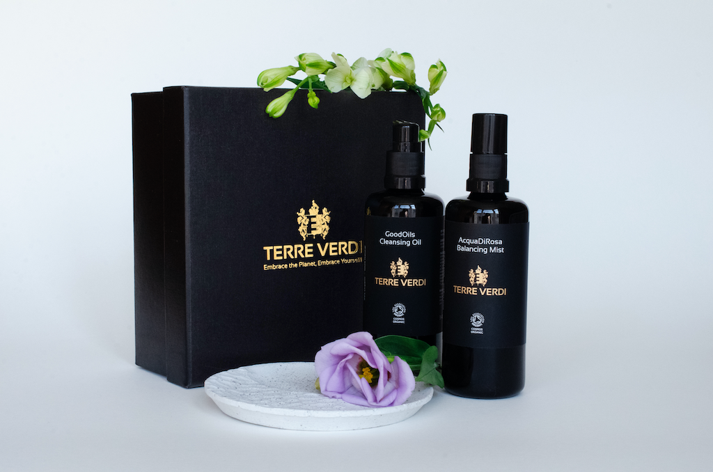 Terre Verdi Organic Cleanser Gift Set. Natural skincare gift set. Both products are in black bottles and stand next to a luxury black box embossed in gold with the Terre Verdi logo and a purple flower sitting in front
