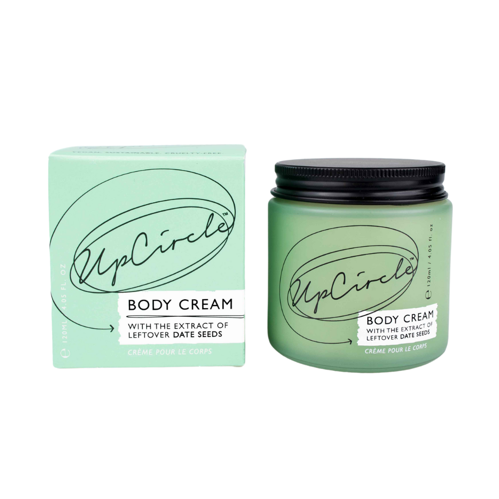 UpCircle Body Cream with Aloe Vera and Cocoa Butter. Sustainable body products. The green glass jar with the Upcircle logo is sitting next to its green box.