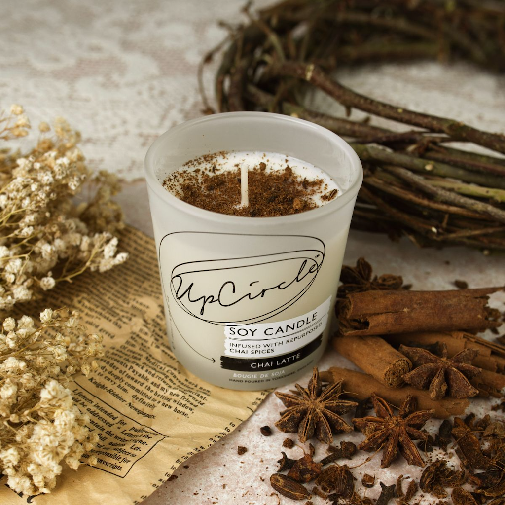 Upcircle Chai Latte Soy Candle. Vegan Christmas gifts. The candle is shown surrounded by herbs and spices traditionally associated with chai tea.