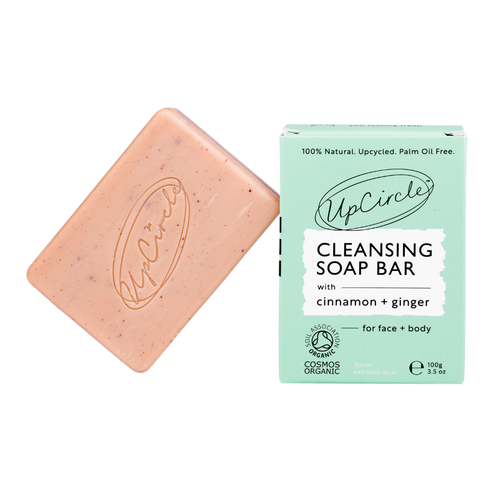 UpCircle Cleansing Soap Bar with Cinnamon and Ginger. Certified organic soap. The pink soap bar is leaning against its green branded box.