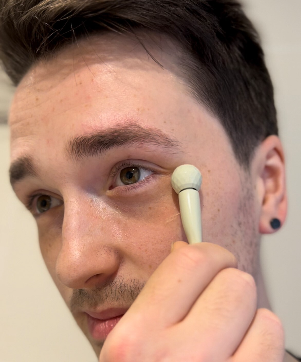 how to use the upcircle eye roller tool. Photo of a man with brown hair and eyes rolling the eye roller underneath the eye area