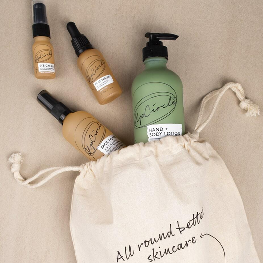 upcircle drawstring bag is the ideal gift wrap. you can see some glass bottles in green and orange containing upcircles natural, upcycled skincare products peeking out of the top of the bag