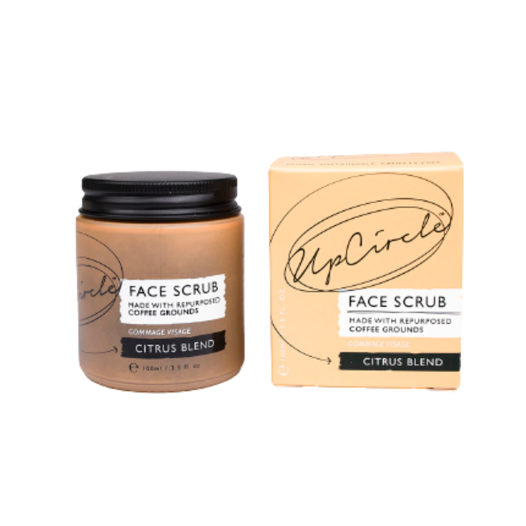 upcircle citrus face scrub shown outside of the peach box in an orange glass jar to the left with black aluminium lid. Label reads 'face scrub made with repurposed coffee grounds citrus blend'