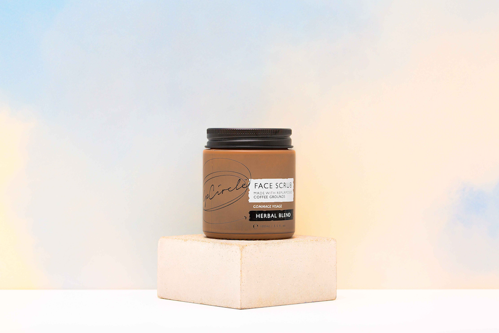 upcircle herbal blend face exfoliator with upcycled coffee grounds is sitting on a square concrete block on a creamy background