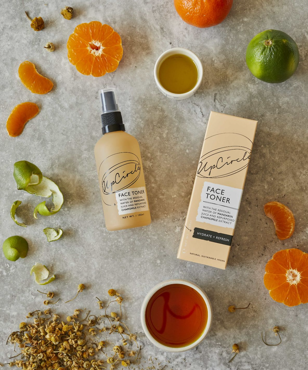 flat lay of upcircle face toner spritz surrounded by oranges, limes and chamomile which are all ingredients in the toner