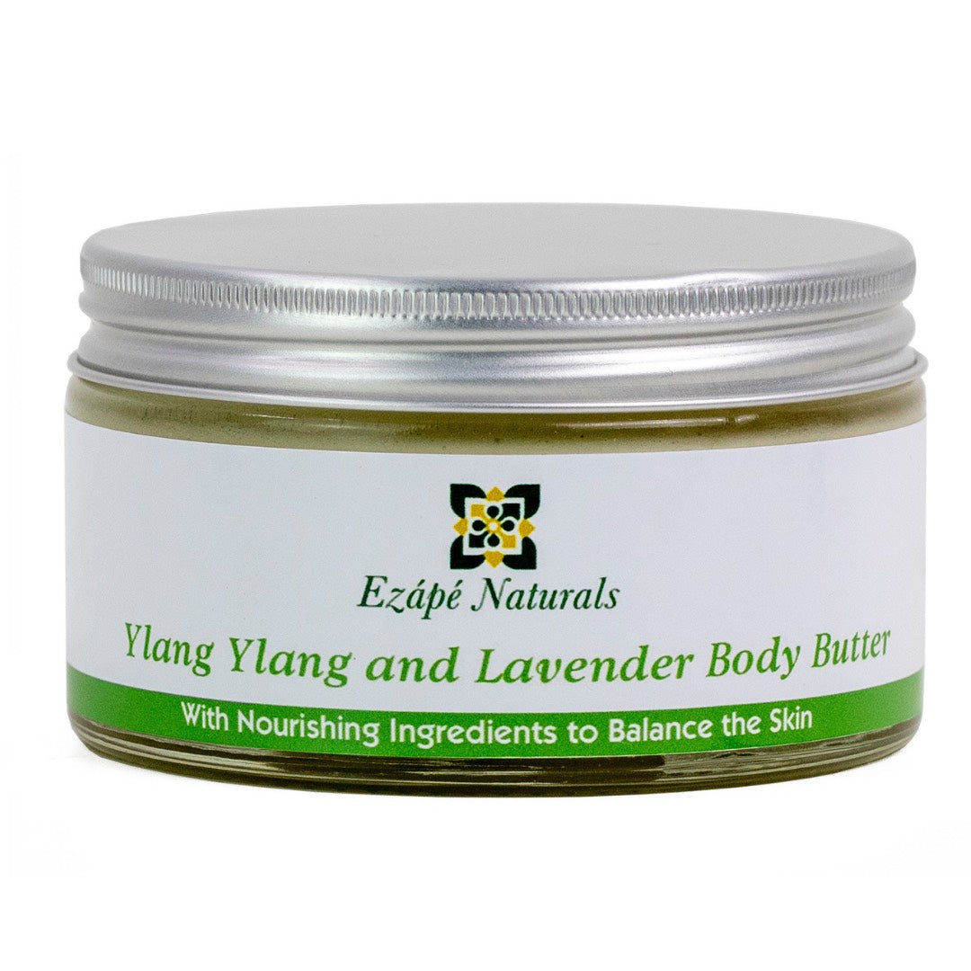 Ylang ylang and Lavender body butter in large size, which is handmade by ezape naturals is photographed on a white background. the body cream comes in a clear glass jar with a silver aluminium lid. the label is white with an green coloured band along the bottom and reads 'ezape naturals Ylang ylang and Lavender body butter with nourishing ingredients to balance the skin'